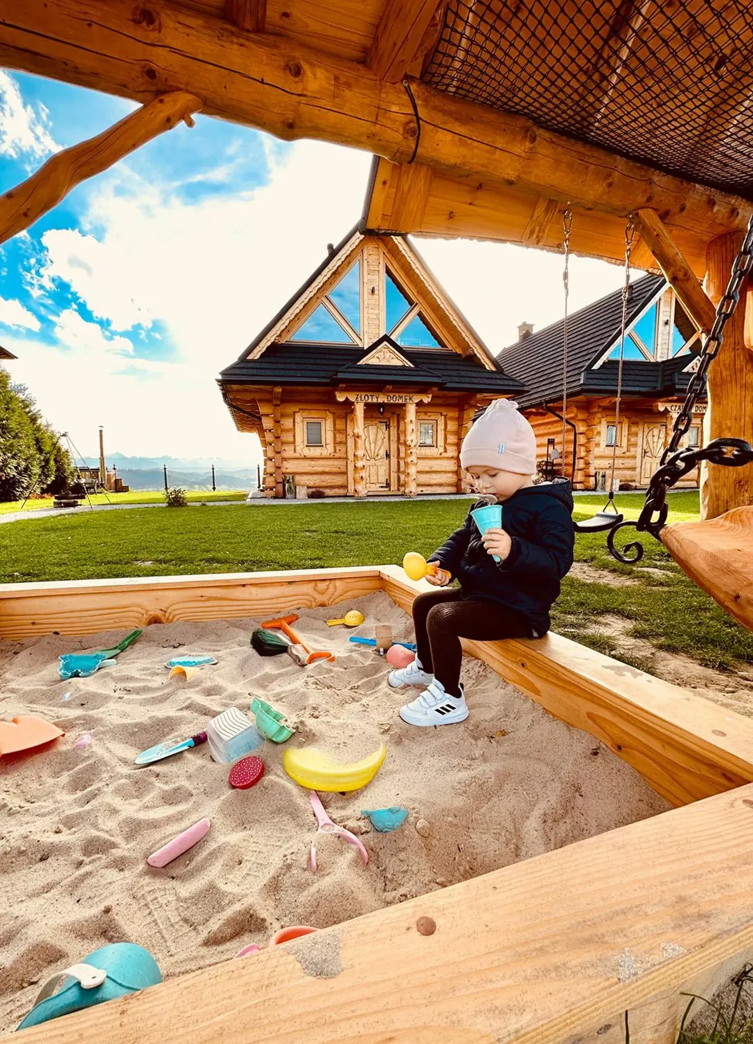 Dziecko przy piaskownicy – domek z bali i widok na Tatry