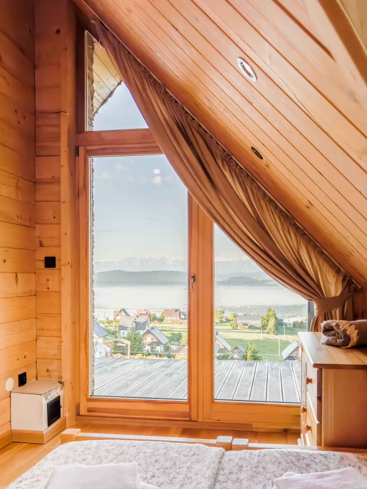 Widok z sypialni na Tatry przez panoramiczne okno o poranku