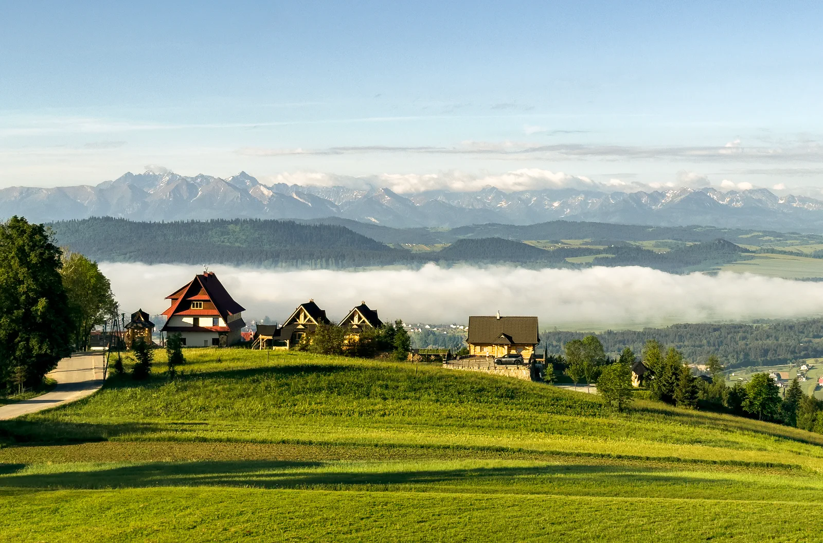 Domki z bali Huba Home na wzgórzu, szeroka panorama Tatr o poranku