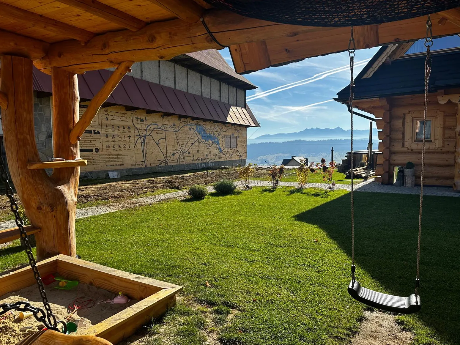 Plac zabaw dla dzieci przy domkach z bali z widokiem na Tatry