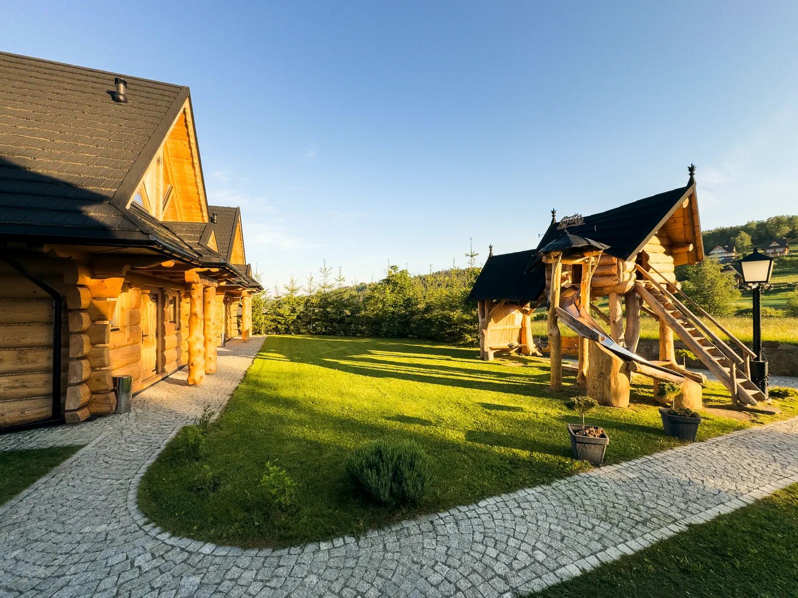 Podwórko Huba Home z drewnianym placem zabaw o poranku